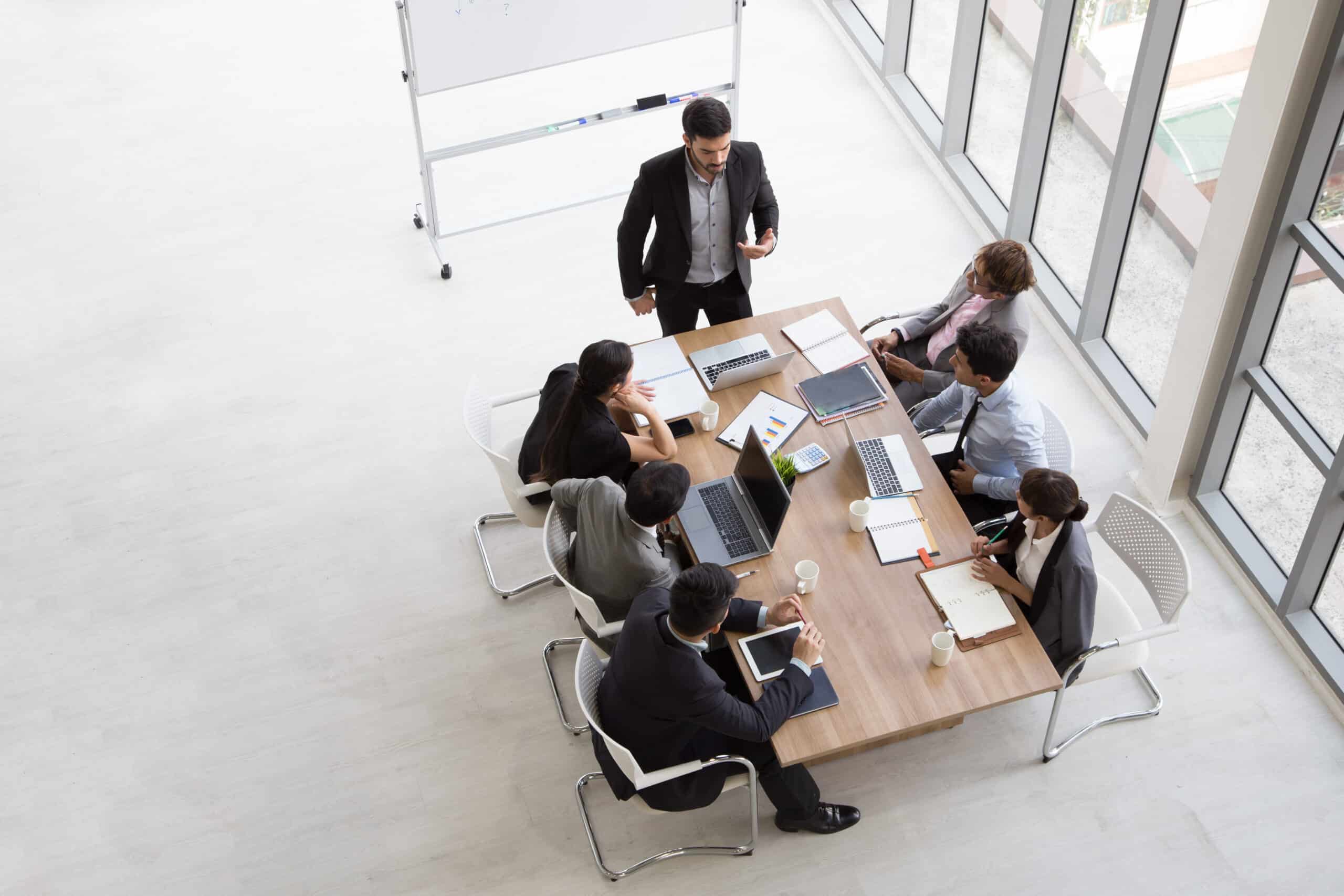 Top view of group of multiethnic busy people working in an office, Aerial view with businessman and businesswoman sitting around a conference table with blank copy space, Business meeting concept