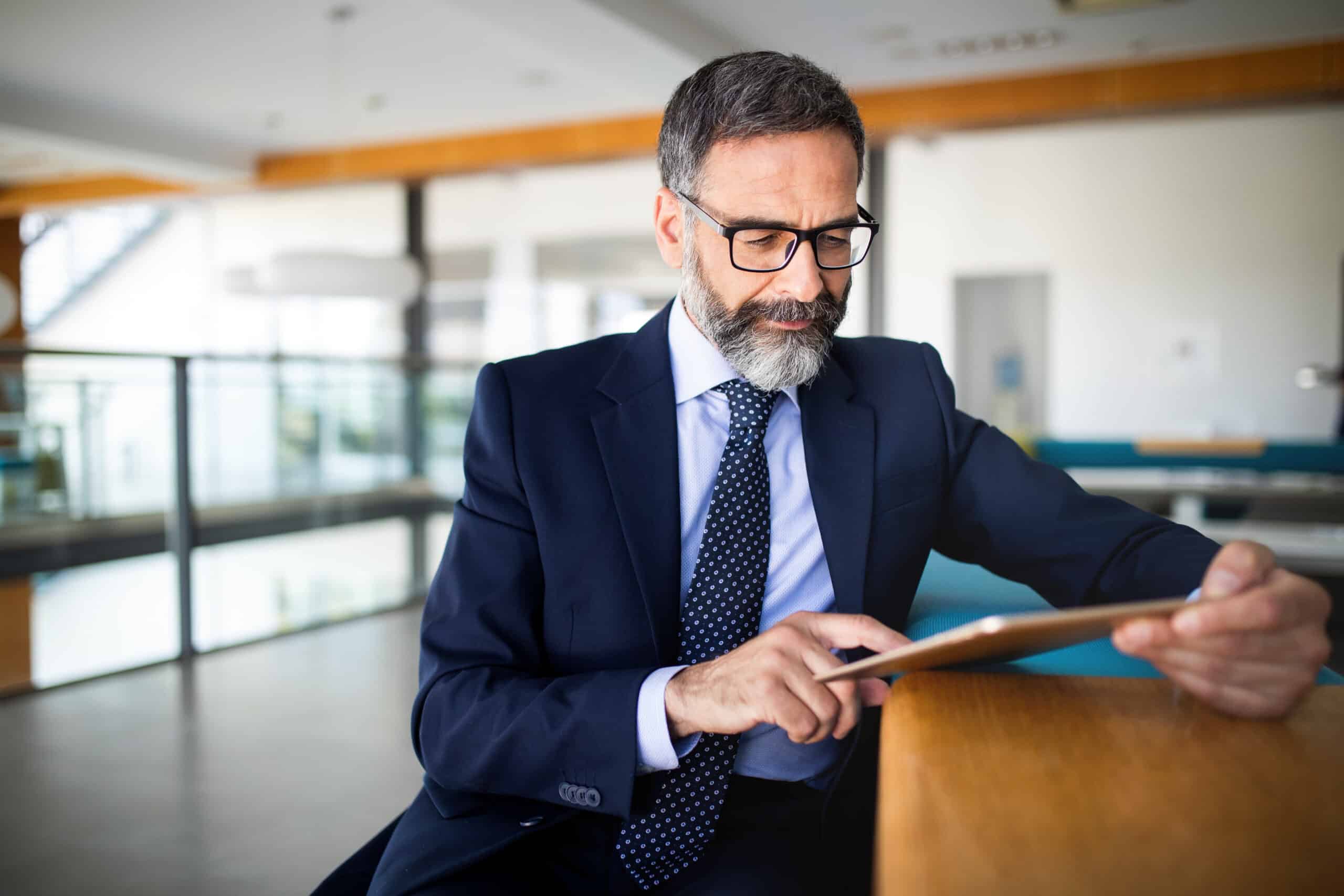 Portrait of handsome senior businessman with digital tablet in office