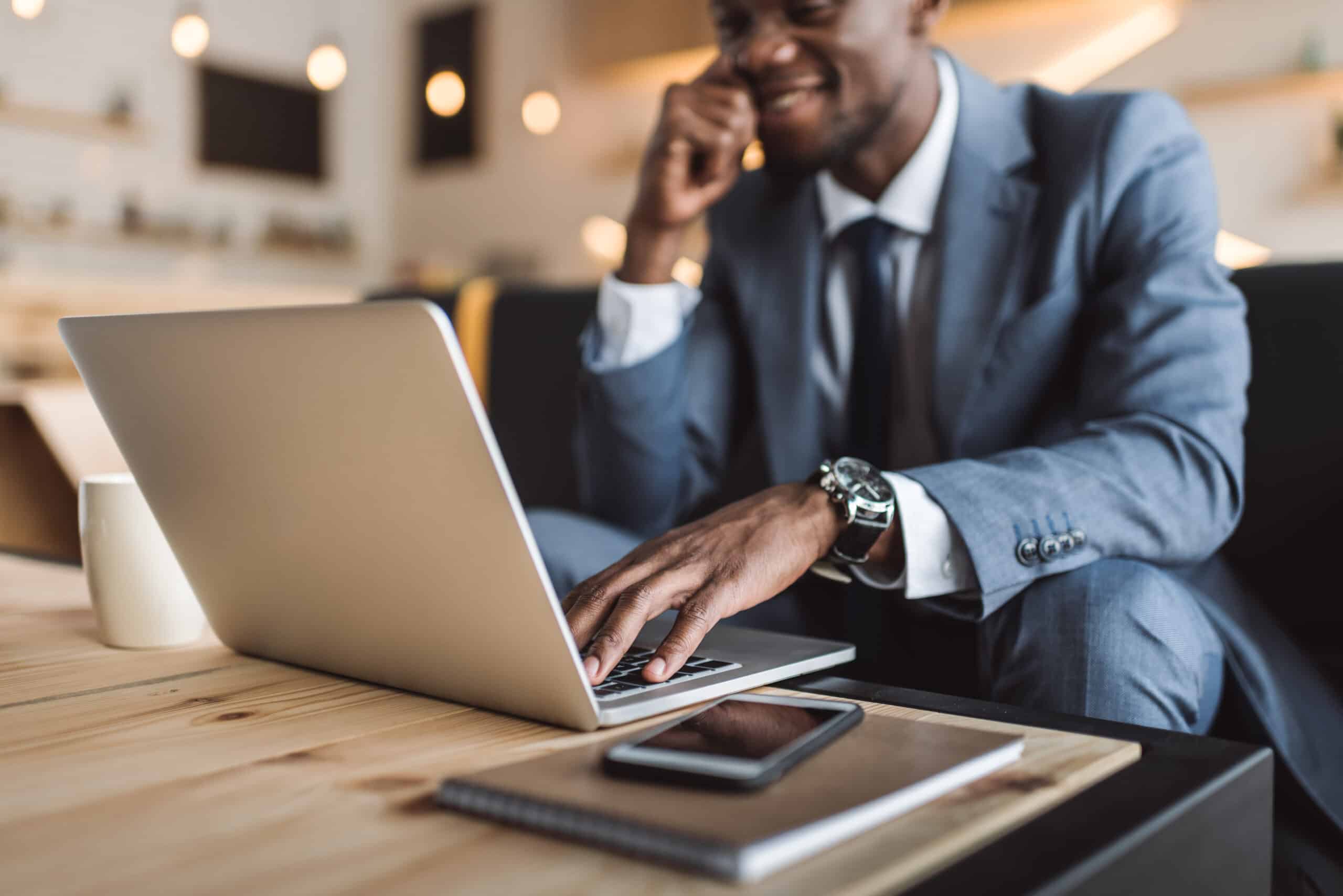 selective focus of handsome african american businessman using laptop in cafe