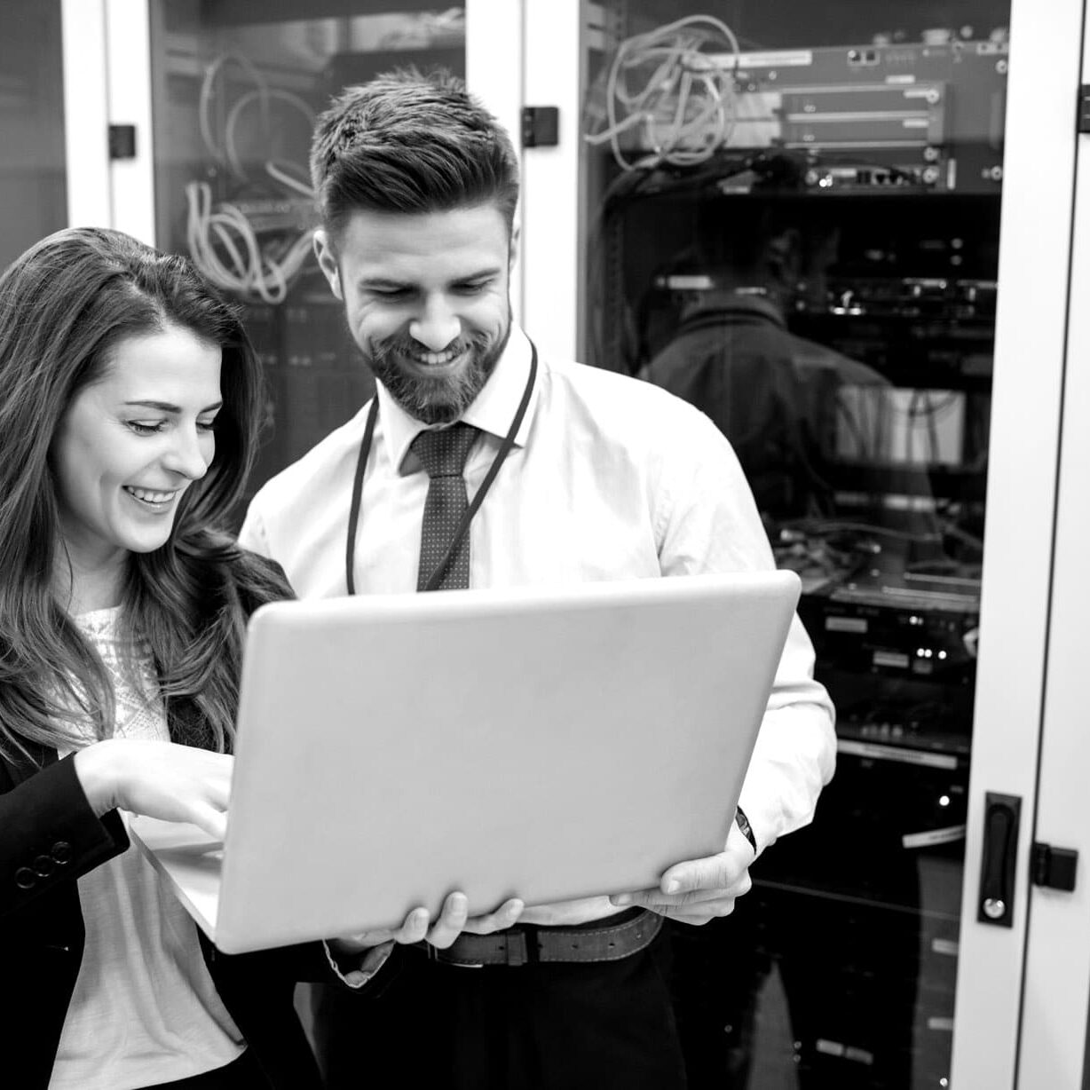 black and white photo of a woman and a man holding one laptop
